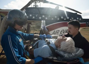 Image of a EMT worker helping a hurt man into the emergency helicopter.