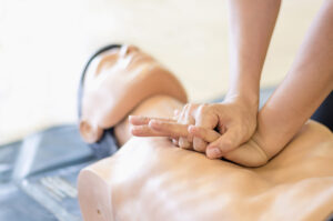 Compresiones torácicas en maniquí durante clase BLS en español en Houston con CPRologist, entrenamiento práctico para certificación de profesionales de la salud.