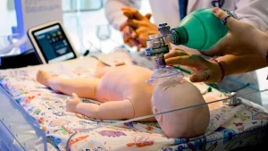 Healthcare providers in neonatal resuscitation program NRP training using bag mask on infant manikin, practicing NRP algorithm skills for NRP certification.