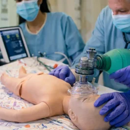 NRP Algorithm Explained: Ventilation, Compressions & Golden Minute Healthcare team practicing neonatal resuscitation program skills on an infant mannequin, using an Ambu bag and tablet with NRP learning platform login during NRP training for NRP certification near me in Houston.